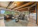 Inviting living room featuring a leather sofa, wood beams, and large windows showcasing beautiful outdoor views at 32462 Lodgepole Dr, Evergreen, CO 80439
