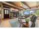 Charming living room with a stone fireplace, wood beams, a leather sofa, and large windows with scenic views at 32462 Lodgepole Dr, Evergreen, CO 80439