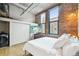 Bedroom featuring exposed brick walls, hardwood floors, and in-unit washer and dryer at 1801 Wynkoop St # 208, Denver, CO 80202