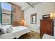 Bedroom featuring exposed brick wall, hardwood floors, and a large window providing natural light at 1801 Wynkoop St # 208, Denver, CO 80202
