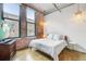 Bedroom featuring exposed brick wall, hardwood floors, and large window with lots of natural light at 1801 Wynkoop St # 208, Denver, CO 80202