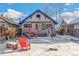 Cozy backyard featuring a charming brick house with blue trim and a patio set under a string of lights, partially covered in snow at 2663 King St, Denver, CO 80211