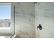Modern shower with white marbled subway tile and black fixtures next to a window at 8555 Hotchkiss St, Littleton, CO 80125