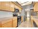 Kitchen featuring wood cabinetry, stainless steel appliances, and a view to the hallway, creating a functional space at 10142 Josephine St, Thornton, CO 80229