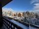 Scenic winter view from the balcony of a mountain home, showcasing snow-covered trees and a clear blue sky at 30819 Hilltop Dr, Evergreen, CO 80439