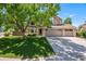 Charming two-story home with a three-car garage, a landscaped front yard, and a large shade tree at 9673 Pinebrook St, Highlands Ranch, CO 80130
