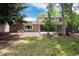 Expansive backyard with brick home, patio, lush lawn, mature trees, and relaxing seating at 9837 E Aberdeen Ave, Englewood, CO 80111