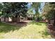 Large backyard featuring a brick home, green lawn, mature trees, shed, and a cozy patio at 9837 E Aberdeen Ave, Englewood, CO 80111