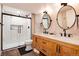 Modern bathroom featuring a double vanity, a walk-in shower, and sleek black hardware at 9837 E Aberdeen Ave, Englewood, CO 80111