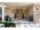 Cozy front porch with brick details, a wood front door, and decorative planters at 9837 E Aberdeen Ave, Englewood, CO 80111