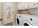 Functional laundry room with white cabinets, washer, and dryer, and access to the backyard at 9837 E Aberdeen Ave, Englewood, CO 80111