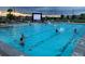 Community swimming pool at dusk, full of swimmers enjoying an outdoor movie at 3231 Lump Gulch Way, Erie, CO 80516