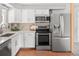 Modern kitchen features stainless steel appliances, white cabinets, and sleek countertops at 6353 W 78Th Ave, Arvada, CO 80003