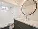 Modern bathroom featuring a walk-in shower, stylish vanity with a round mirror, and sleek fixtures at 2076 S Yates St, Denver, CO 80219