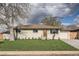 Charming single-story home featuring a freshly manicured lawn, newer windows, and an eye-catching orange-colored front door at 2076 S Yates St, Denver, CO 80219