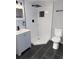 Modern bathroom featuring a tiled shower with a rainfall showerhead, sleek vanity, and black tile floors at 2619 S Bannock St, Denver, CO 80223