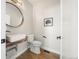 Modern powder room with a vessel sink, rustic wood counter, round mirror and gray walls at 3485 S Clermont St, Denver, CO 80222