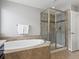 Modern bathroom with a soaking tub, glass-enclosed shower, and neutral tile accents at 5439 Verbena St, Denver, CO 80238