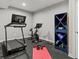 Basement exercise room with a treadmill, workout bike, rubber floor, and custom shelving for weights at 5439 Verbena St, Denver, CO 80238