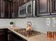 Close-up of a kitchen featuring granite countertops, a stylish stovetop, and stainless-steel microwave and backsplash at 5439 Verbena St, Denver, CO 80238