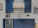 Basement kitchenette features blue cabinets, sink, light countertops, shelves, and a beverage refrigerator at 5439 Verbena St, Denver, CO 80238
