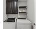Laundry room features new Whirlpool washer and dryer set, floating shelves, and dark brown cabinets at 5439 Verbena St, Denver, CO 80238