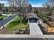 An aerial view shows a home with an attached garage, long driveway, garden beds and fenced backyard at 180 Dover St, Lakewood, CO 80226
