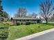 Charming single-story brick home with a well-maintained lawn and manicured landscaping, set under a clear blue sky at 180 Dover St, Lakewood, CO 80226