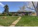 Inviting single-story home with a lush green lawn, mature trees, and a pathway leading to the entrance at 180 Dover St, Lakewood, CO 80226