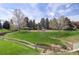 Community playground surrounded by mature trees and grassy fields, offering a safe and fun recreational space at 180 Dover St, Lakewood, CO 80226