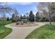 Neighborhood playground offering a slide, swings, and roundabout within a circular, mulched area at 180 Dover St, Lakewood, CO 80226