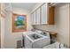 Laundry room featuring a modern washer and dryer, storage cabinets, and a window with a view at 8000 S Williams Way, Centennial, CO 80122