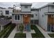 Modern three-story townhome featuring brick and wood accents, a rooftop patio, and a bright blue front door at 1355 Zenobia St, Denver, CO 80204