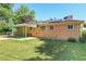 Brick house with a covered patio and lush green lawn, perfect for outdoor activities and relaxation at 3354 W Arlington Ave, Littleton, CO 80123