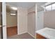 Small bathroom area with tiled shower, wood-paneled walls, and an open doorway to an adjacent carpeted room at 3354 W Arlington Ave, Littleton, CO 80123