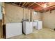 Basement laundry room with exposed ceiling, concrete walls and floor, with washer, dryer and chest freezer at 3354 W Arlington Ave, Littleton, CO 80123