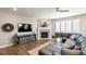 Cozy living room featuring a fireplace, hardwood floors, a plush leather sectional, and ample natural light at 7404 Greenwater Cir, Castle Rock, CO 80108