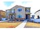 Inviting townhome featuring stone accents, covered front porch and concrete walkway at 5154 Bittercress Rd, Brighton, CO 80640