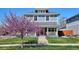 Charming two-story home featuring a welcoming front porch and a well-manicured lawn with a beautiful tree in bloom at 2801 Cherry St, Denver, CO 80207