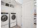 Modern laundry room with white appliances, tile floor, and a storage shelf at 2801 Cherry St, Denver, CO 80207