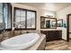 Luxurious bathroom featuring a soaking tub under a window and a double vanity with framed mirrors at 23965 E Kettle Pl, Aurora, CO 80016