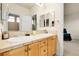 Bright bathroom featuring a double sink vanity with tile countertops, framed mirror, and access to a tiled shower at 23965 E Kettle Pl, Aurora, CO 80016