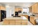 Spacious kitchen with large island, black appliances, light wood cabinetry, and granite counters at 23965 E Kettle Pl, Aurora, CO 80016