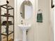 Charming powder room with pedestal sink, oval mirror, and decorative storage shelf at 23965 E Kettle Pl, Aurora, CO 80016
