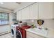Well-equipped laundry room with modern washer and dryer, ample storage cabinets, and a functional utility sink at 824 S Medea Way, Denver, CO 80209