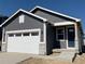 Charming gray house boasts a white garage door, stone accents, and a covered entryway with a dark blue door at 9085 Rifle St, Commerce City, CO 80022