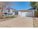 Well-manicured front yard with charming white brick facade, two-car garage, and classic black window trim at 16543 E Kansas Pl, Aurora, CO 80017