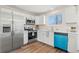 Updated kitchen with white cabinets, stainless steel appliances, and a bright blue dishwasher at 16543 E Kansas Pl, Aurora, CO 80017
