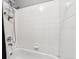 Bright white tiled bathroom with a bathtub-shower combination and shower rack at 1953 E 102Nd Cir, Thornton, CO 80229