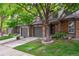 Charming townhome featuring brick accents, a gray garage door, and a well-manicured lawn with a mature shade tree at 1953 E 102Nd Cir, Thornton, CO 80229